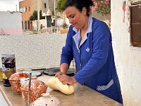 She is making bread to sell to passers-by
